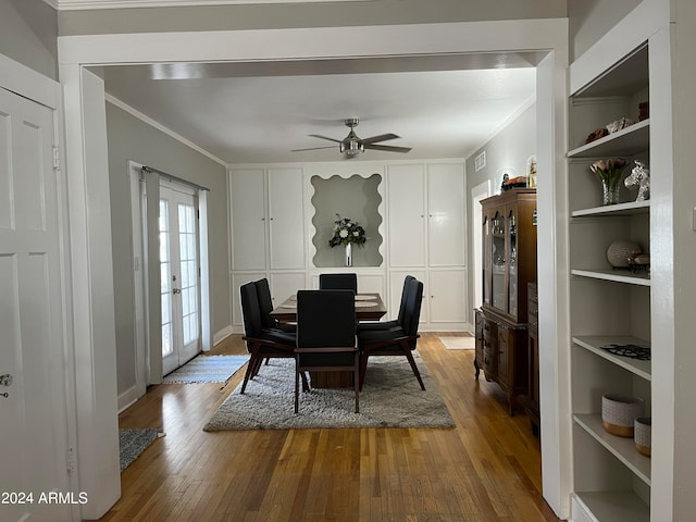 dining space with wood-type flooring, crown molding, ceiling fan, french doors, and built in shelves