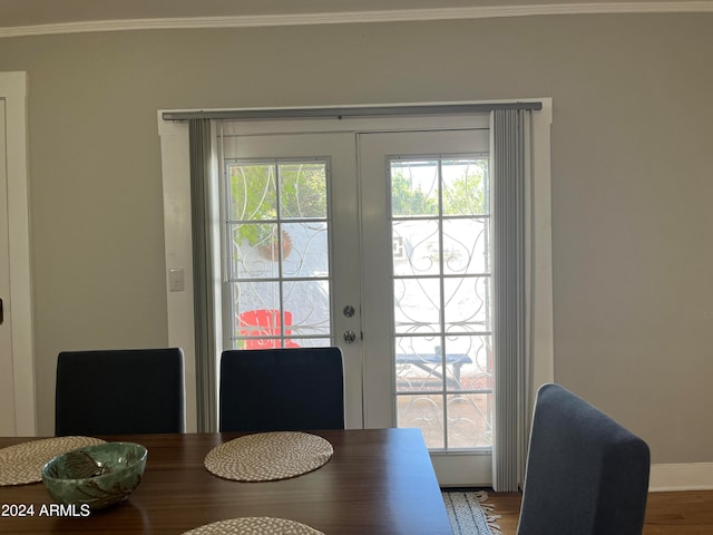 dining space with wood-type flooring, ornamental molding, and french doors