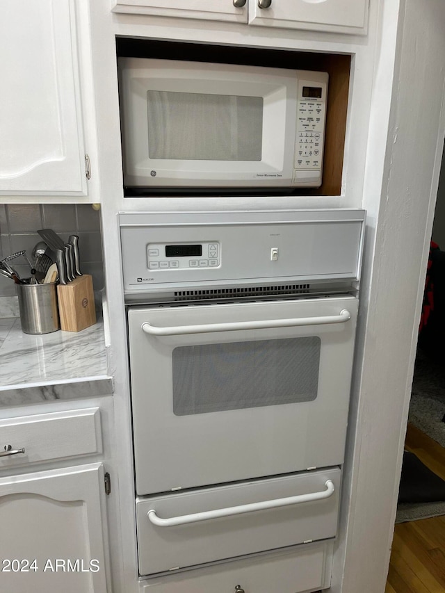 details featuring white cabinets, multiple ovens, and tasteful backsplash