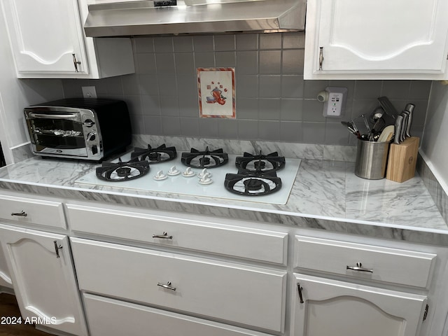 kitchen featuring decorative backsplash, white gas cooktop, extractor fan, and white cabinets