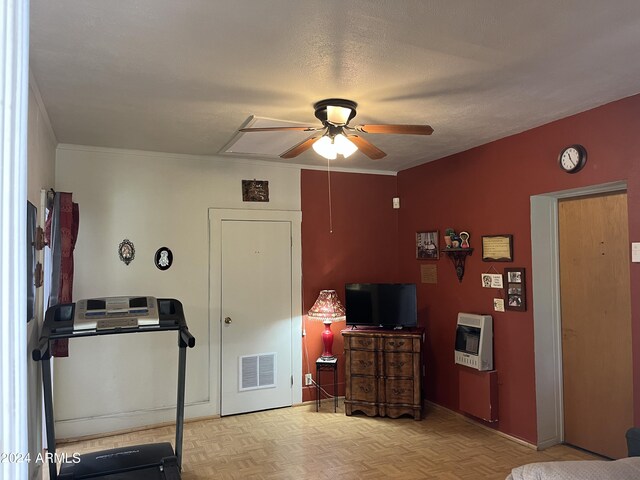 bedroom featuring heating unit, a textured ceiling, light parquet flooring, crown molding, and ceiling fan