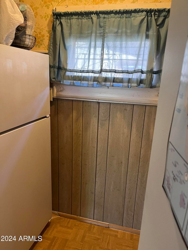 kitchen featuring white refrigerator, wood walls, and light parquet flooring