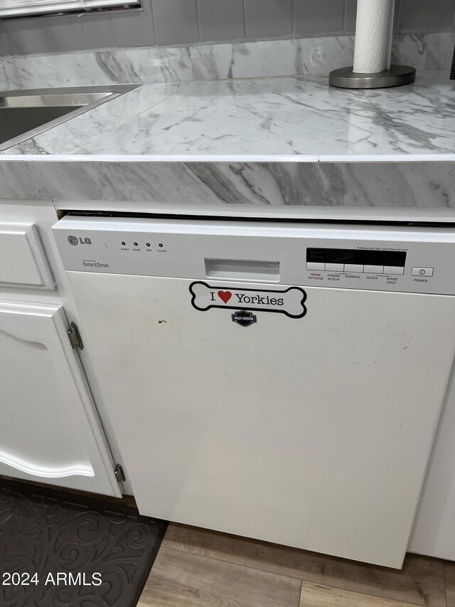 interior details with white dishwasher, hardwood / wood-style floors, and white cabinetry