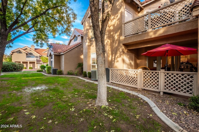 view of property exterior with a lawn, central AC unit, and a balcony