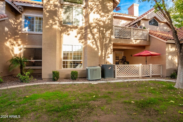 rear view of property featuring a lawn and cooling unit