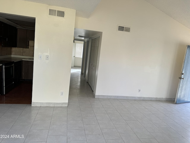 tiled spare room with a textured ceiling and high vaulted ceiling