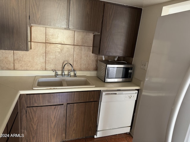 kitchen featuring backsplash, sink, dark tile patterned floors, and white appliances