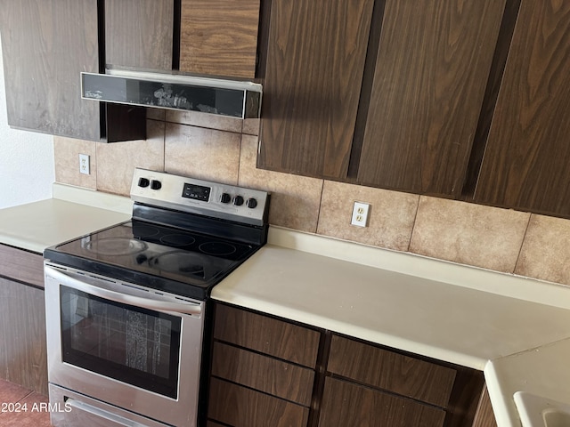 kitchen featuring tasteful backsplash, stainless steel electric range oven, and dark brown cabinets