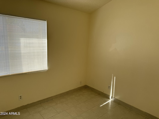 tiled spare room with a textured ceiling