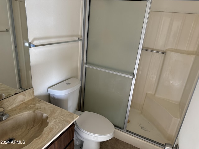 bathroom with toilet, a shower with door, vanity, and tile patterned flooring