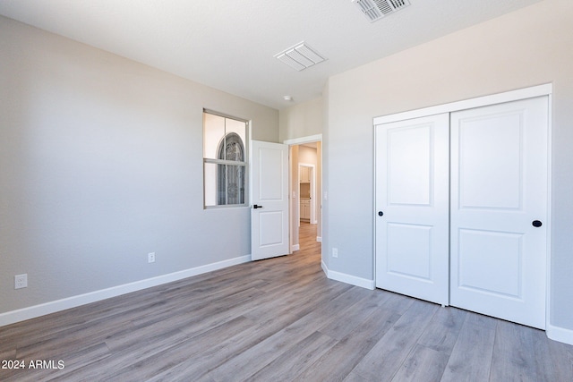 unfurnished bedroom featuring light hardwood / wood-style flooring and a closet