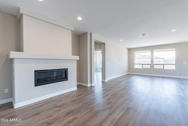 unfurnished living room featuring a textured ceiling and hardwood / wood-style floors