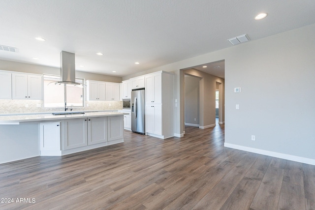 kitchen with white cabinets, hardwood / wood-style floors, island exhaust hood, a healthy amount of sunlight, and stainless steel refrigerator with ice dispenser