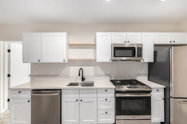 kitchen featuring appliances with stainless steel finishes, white cabinets, a sink, and open shelves