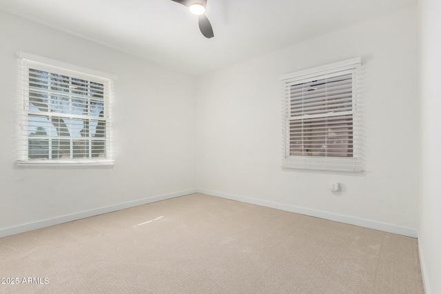 unfurnished room with a ceiling fan, light carpet, and baseboards