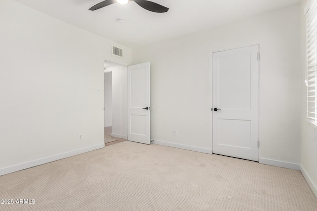 unfurnished bedroom featuring a ceiling fan, visible vents, light carpet, and baseboards