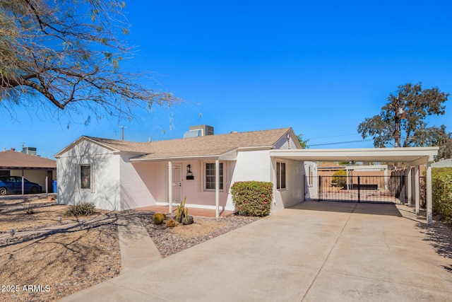 ranch-style house featuring a carport, concrete driveway, fence, and stucco siding