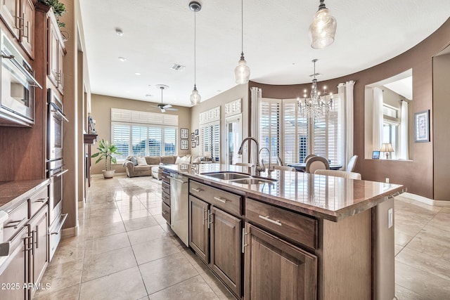 kitchen featuring pendant lighting, stainless steel appliances, sink, a kitchen island with sink, and light tile patterned floors