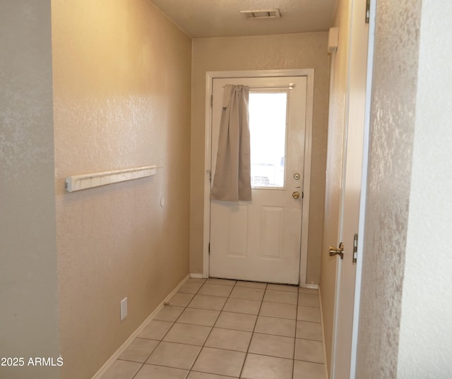 doorway to outside with visible vents, baseboards, and light tile patterned floors