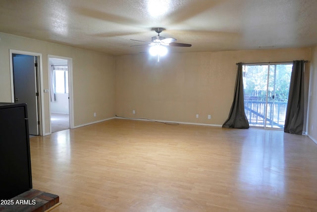 empty room featuring a healthy amount of sunlight, light wood-style flooring, and a textured ceiling