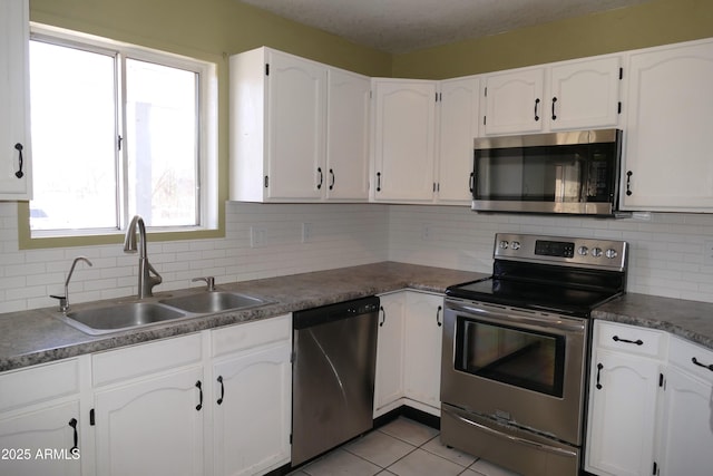 kitchen featuring light tile patterned floors, stainless steel appliances, a sink, and white cabinets