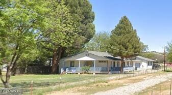 view of front facade featuring covered porch, fence, and a front yard