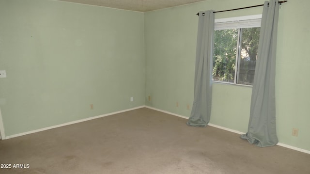 empty room featuring carpet flooring and baseboards