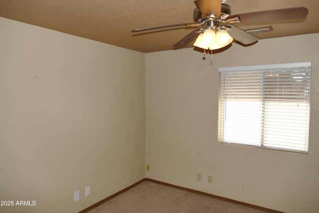 spare room featuring light carpet, ceiling fan, visible vents, and baseboards