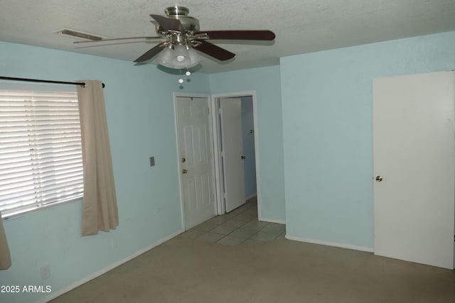 unfurnished bedroom with baseboards, ceiling fan, visible vents, and a textured ceiling