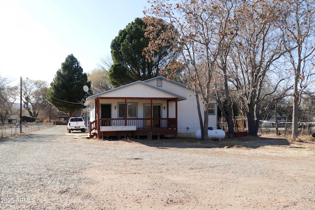 view of front facade with covered porch, driveway, and fence