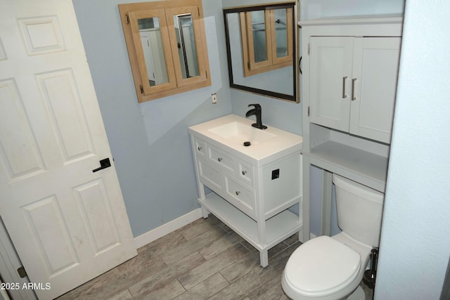 bathroom with toilet, baseboards, wood finished floors, and vanity