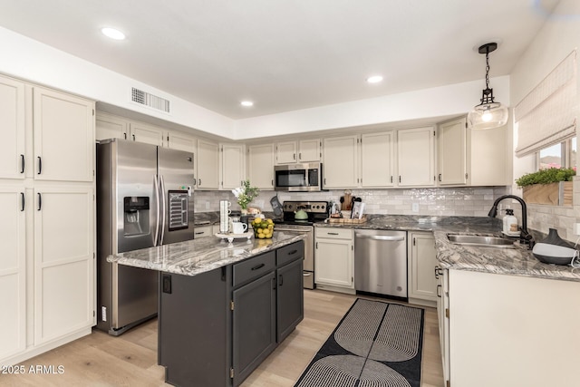 1202 E Libby St, Phoenix, AZ 85022 - kitchen with stainless steel appliances, a sink, a center island, light stone counters, and light wood-type flooring