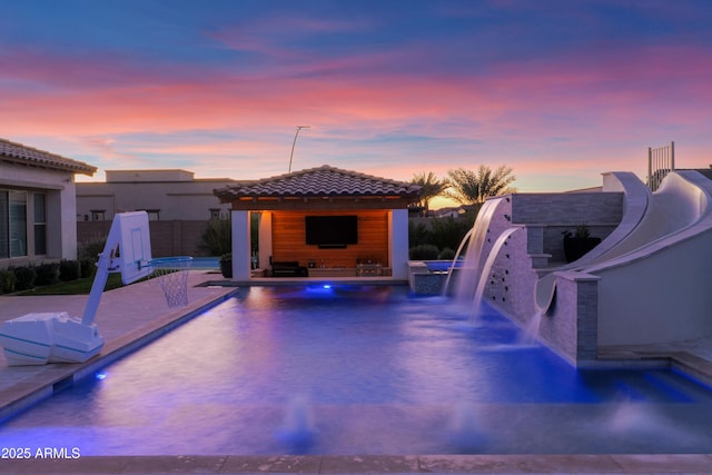 view of swimming pool with pool water feature and a patio