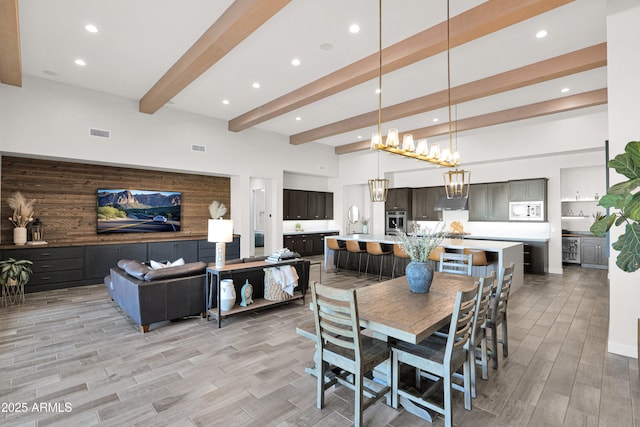 dining room with a chandelier, beamed ceiling, and a high ceiling