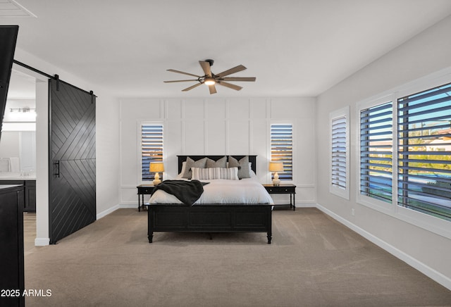 carpeted bedroom with ceiling fan, ensuite bathroom, and a barn door