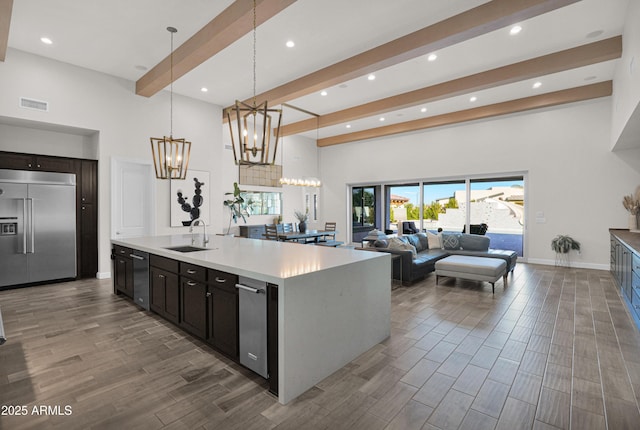 kitchen with a chandelier, sink, decorative light fixtures, stainless steel appliances, and a center island with sink