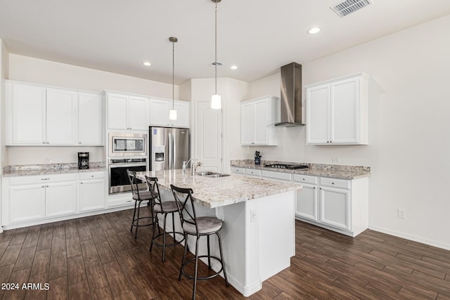 kitchen with a breakfast bar area, visible vents, a sink, appliances with stainless steel finishes, and wall chimney range hood