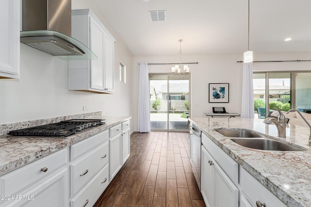 kitchen with visible vents, wood finish floors, wall chimney range hood, appliances with stainless steel finishes, and a sink