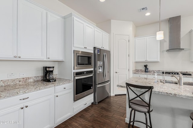 kitchen with visible vents, white cabinetry, appliances with stainless steel finishes, and wall chimney range hood