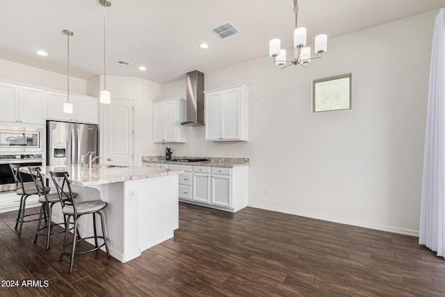 kitchen featuring a kitchen bar, visible vents, stainless steel appliances, wall chimney range hood, and dark wood-style flooring