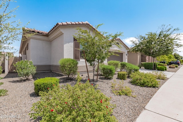 view of home's exterior with a tile roof, fence, a garage, and stucco siding