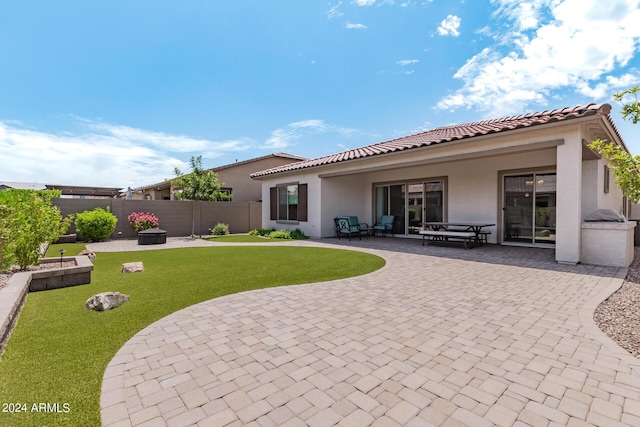 back of house featuring stucco siding, a lawn, a tile roof, fence, and a patio area