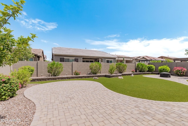 view of front of property featuring a fenced backyard, stucco siding, a front lawn, a fire pit, and a patio area