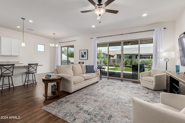 living room with ceiling fan with notable chandelier, recessed lighting, dark wood-style flooring, and baseboards