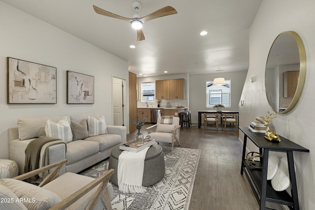 living room with ceiling fan, sink, and dark wood-type flooring