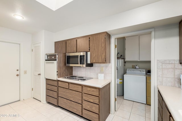 kitchen featuring light tile patterned floors, tasteful backsplash, stainless steel appliances, light countertops, and water heater