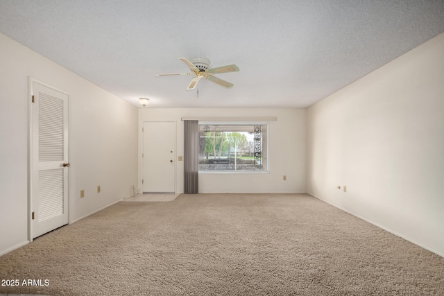 spare room with ceiling fan, a textured ceiling, and light colored carpet