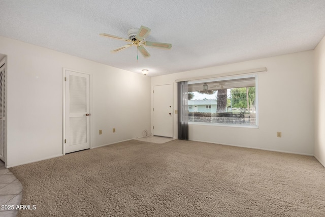 carpeted empty room featuring a ceiling fan and a textured ceiling