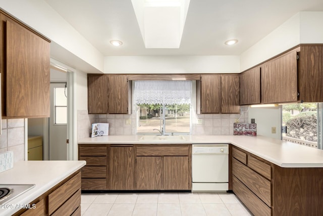 kitchen with light countertops, decorative backsplash, light tile patterned flooring, a sink, and dishwasher