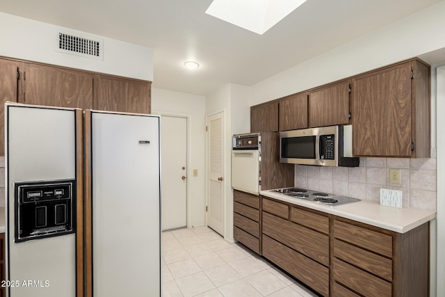 kitchen featuring a skylight, visible vents, decorative backsplash, stainless steel appliances, and light countertops